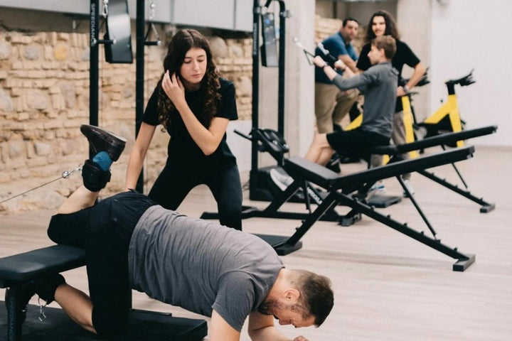A trainer coaching a client in a stone-walled studio